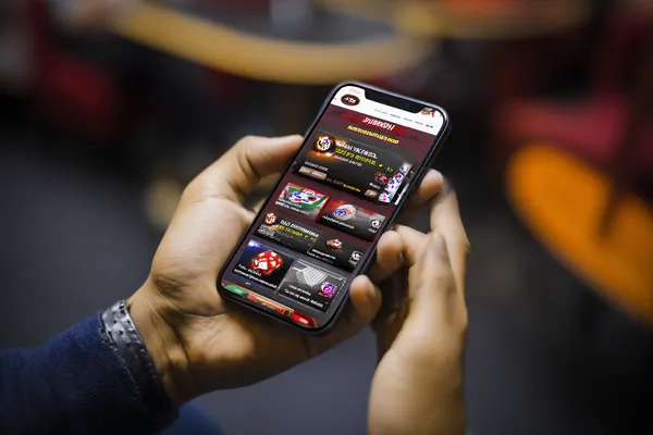 A man focused on his laptop with live stats in the background, highlighting the dedicated sports and gaming features of the 5666BDT mobile app.